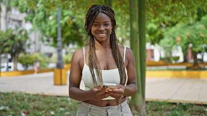 african american woman using smartphone smiling at park