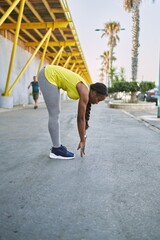 Sticker - African american woman wearing sportswear stretching leg at street