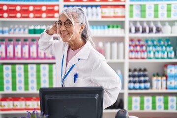 Poster - Middle age woman with tattoos working at pharmacy drugstore smiling doing phone gesture with hand and fingers like talking on the telephone. communicating concepts.