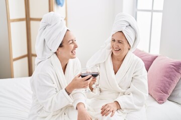 Sticker - Mother and daughter wearing bathrobe drinking glass of wine at bedroom