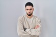 © Krakenimages.com - Young handsome man standing over isolated background skeptic and nervous, disapproving expression on face with crossed arms. negative person.