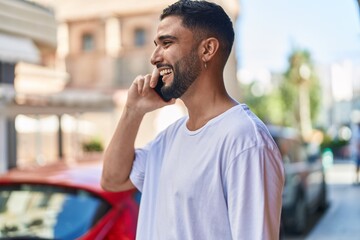 Wall Mural - Young arab man smiling confident talking on the smartphone at street