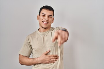 Young arab man wearing casual t shirt laughing at you, pointing finger to the camera with hand over body, shame expression