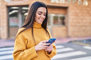 Wall Mural - Young hispanic woman smiling confident using smartphone at street