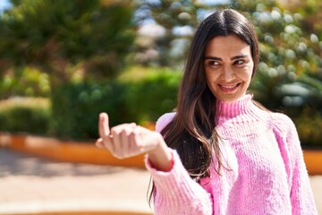 Wall Mural - Young hispanic woman smiling confident doing coming gesture with finger at park