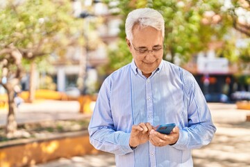 Wall Mural - Senior man smiling confident using smartphone at park