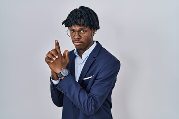 Poster - Young african man with dreadlocks wearing business jacket over white background holding symbolic gun with hand gesture, playing killing shooting weapons, angry face