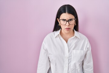 Poster - Young brunette woman standing over pink background skeptic and nervous, frowning upset because of problem. negative person.