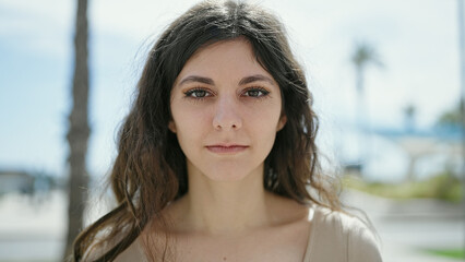 Young beautiful hispanic woman standing with serious expression at street