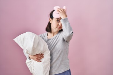 Canvas Print - Woman with down syndrome wearing sleeping mask hugging pillow surprised with hand on head for mistake, remember error. forgot, bad memory concept.