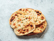 Fresh naan bread on plate over gray cement background. Several perfect naan flatbreads