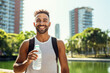 © BrightSpace - a cheerful athletic man takes a refreshing break from jogging in the radiant park, sipping water with a smile. His healthy lifestyle and fit physique showcase the joys of staying active, gen ai