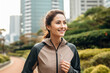 © BrightSpace - Vibrant Midlife Woman Exercising Outdoors: Beautiful Lady portrait people jogging with Freshness in Urban Park with Trees and Buildings with bright sun and nature light, healthy concept, gen ai