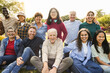 Group of multigenerational people smiling in front of camera - Multiracial friends of different ages having fun together - Main focus on asian center girl face