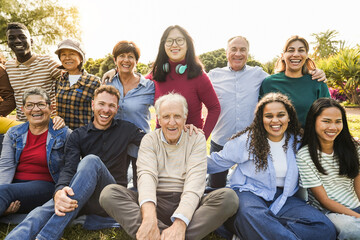 group of multigenerational people smiling in front of camera - multiracial friends of different ages