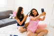 Beautiful teenagers taking selfies while doing their hair in pajamas