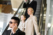 © LIGHTFIELD STUDIOS - personal security concept, bodyguard communicating through earpiece while protecting safety of clients, rich lifestyle, successful woman and preteen daughter standing on escalator of hotel