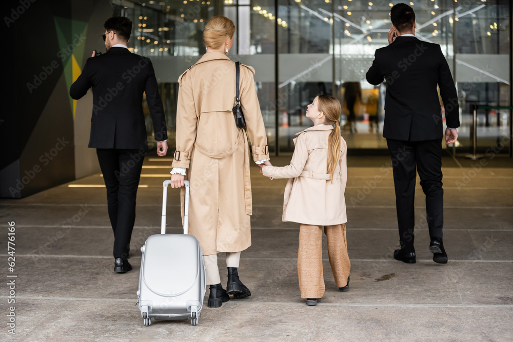 Foto stock di back view of bodyguards walking next to blonde woman and ...