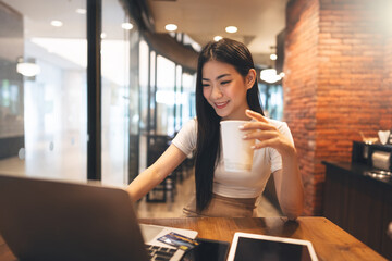 Wall Mural - Happy business freelance asian woman holding coffee cup at cafe urban lifestyle