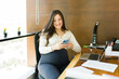 Happy pregnant businesswoman using phone in office