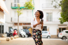 Happy Young African American Woman With Cellphone In City