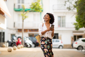 happy young african american woman with cellphone in city