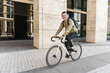 © muse studio - A freelance man riding to work on a bicycle with a bag, to the office on an eco-transport, a millennial in stylish clothes. Listens to music in wireless headphones playlist from the app.
