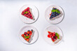 © ricka_kinamoto - Summer cafe baking menu background, sweet cheesecake portion slices with various toppings, jam and berry fruits - strawberry, blueberry, raspberry, cherry