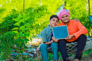 Wall Mural - Cute indian farmer child in school uniform with his father at agriculture field