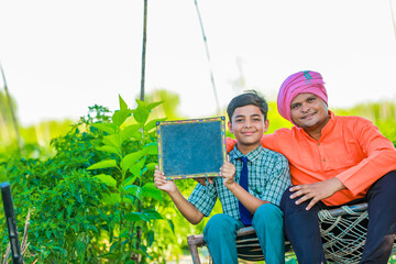 Wall Mural - Cute indian farmer child in school uniform with his father at agriculture field