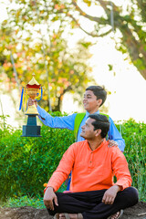 Wall Mural - Cute indian farmer child in school uniform with his father at agriculture field