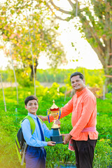 Wall Mural - Cute indian farmer child in school uniform with his father at agriculture field