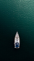 Top down aerial view of a sail boat sailing towards the light