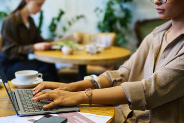 Aufkleber - Hands of young African American businesswoman over laptop keyboard typing while sitting by table in cafe or coworking space during network