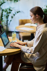 Aufkleber - Young brunette businesswoman in quiet luxury attire sitting by table in front of laptop, typing and analyzing online financial data