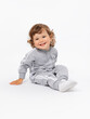 © Andrey_Maksimov - The toddler is 2 years old. A joyful boy is sitting on the floor and laughing with his head tilted with curly hair, plump cheeks in a gray jumpsuit and socks on a white background.
