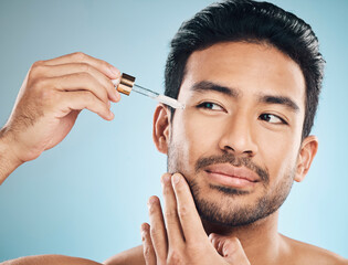 Sticker - Face, beauty and antiaging oil with a man in studio on a blue background for skincare or grooming. Luxury, serum or wellness with a handsome male person in the bathroom to apply a product to his face