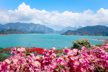 Beautiful point view of Ratchaprapa Dam or Cheow Lan Dam, crystal clear blue freshwater lake with mountains and cloudy sky as background, popular tourist attractions in Surat Thani province, Thailand.