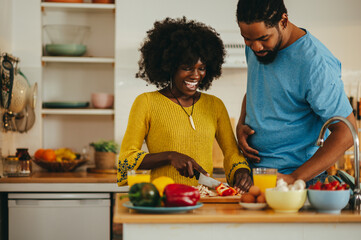 Wall Mural - A happy multiracial couple is cooking an organic vegan lunch at home.