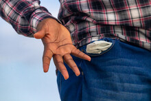 A Contemplative Moment Frozen In Time, Capturing A Man's Hand In His Pocket, Symbolizing His Lack Of Funds And The Need For Financial Assistance.