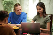 © DragonImages - College students gathered at homw to work on project together