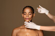 Cosmetic beauty injections concept. Attractive black middle aged woman getting facial injection in cheekbones zone