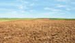 Freshly plowed farmland. The farmland is all moved and furrowed. It is ready to be sown with seeds. It is a sunny day with few clouds blue sky.