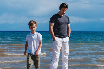 Canvas Print - Father and son after conflict on the lake shore