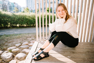 young beautiful girl in white shirt on city street, woman resting outdoors