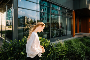 beautiful young girl in white shirt is walking on aity street, woman is resting outdoors