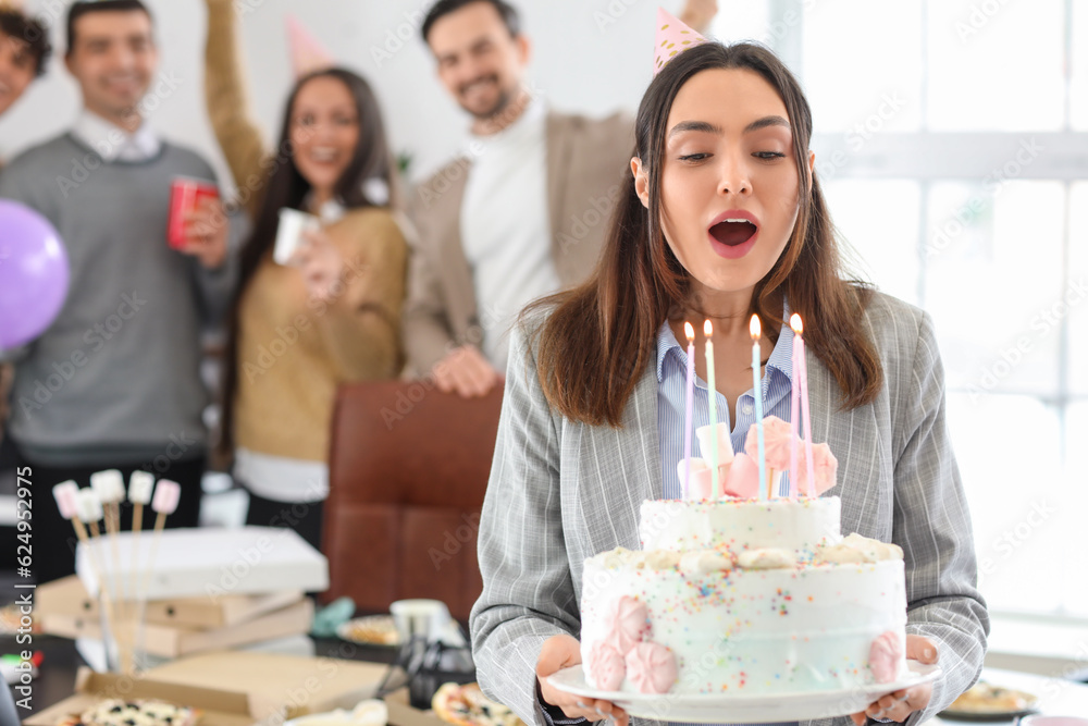 Young woman with Birthday cake making wish at party in office