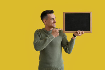 Canvas Print - Male teacher pointing at chalkboard on yellow background