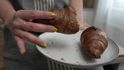 Wall Mural - happy young adult caucasian woman eat croissants in the kitchen