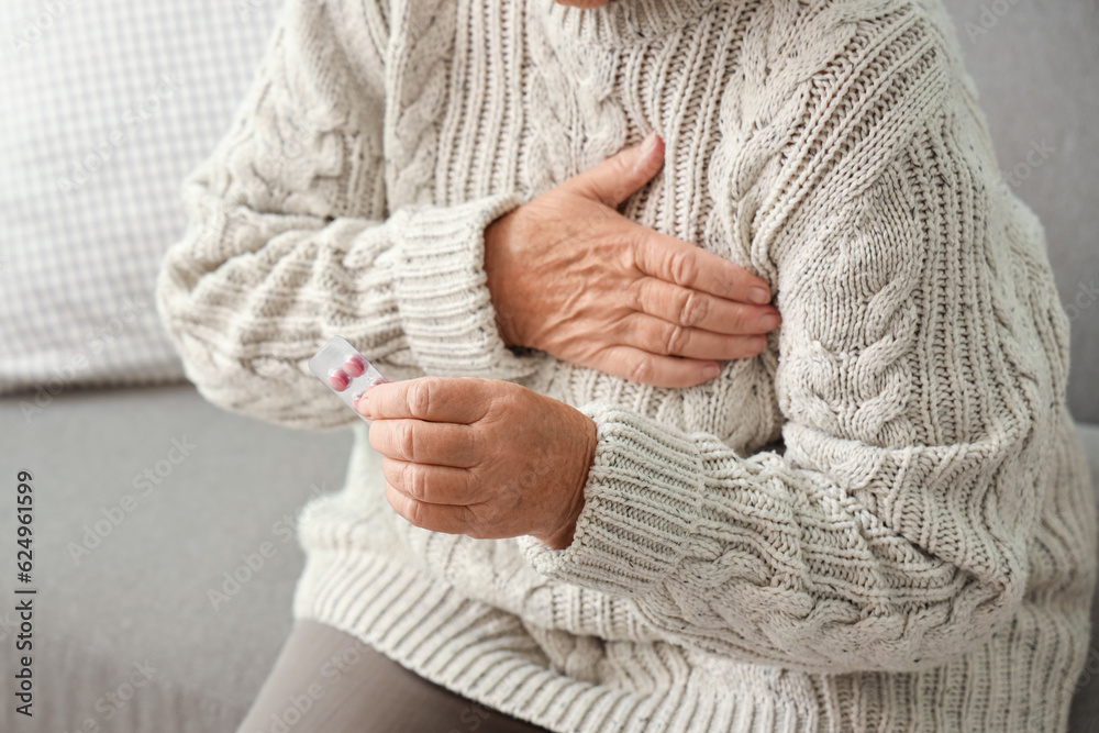 Elderly woman with pills having heart attack at home